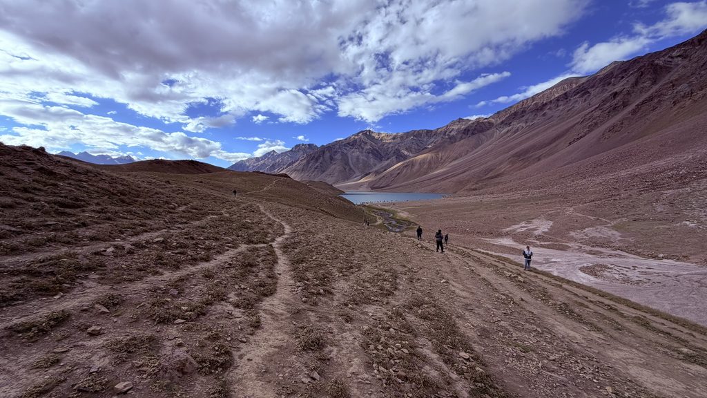 Wide view of Chandratal Lake with mountain trails and dramatic sky in Spiti Valley, Himachal Pradesh