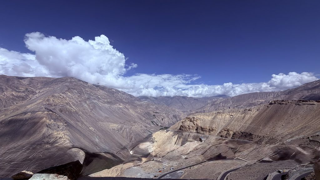 Kinnaur highway winding through Spiti valley mountains with river below and dramatic clouds