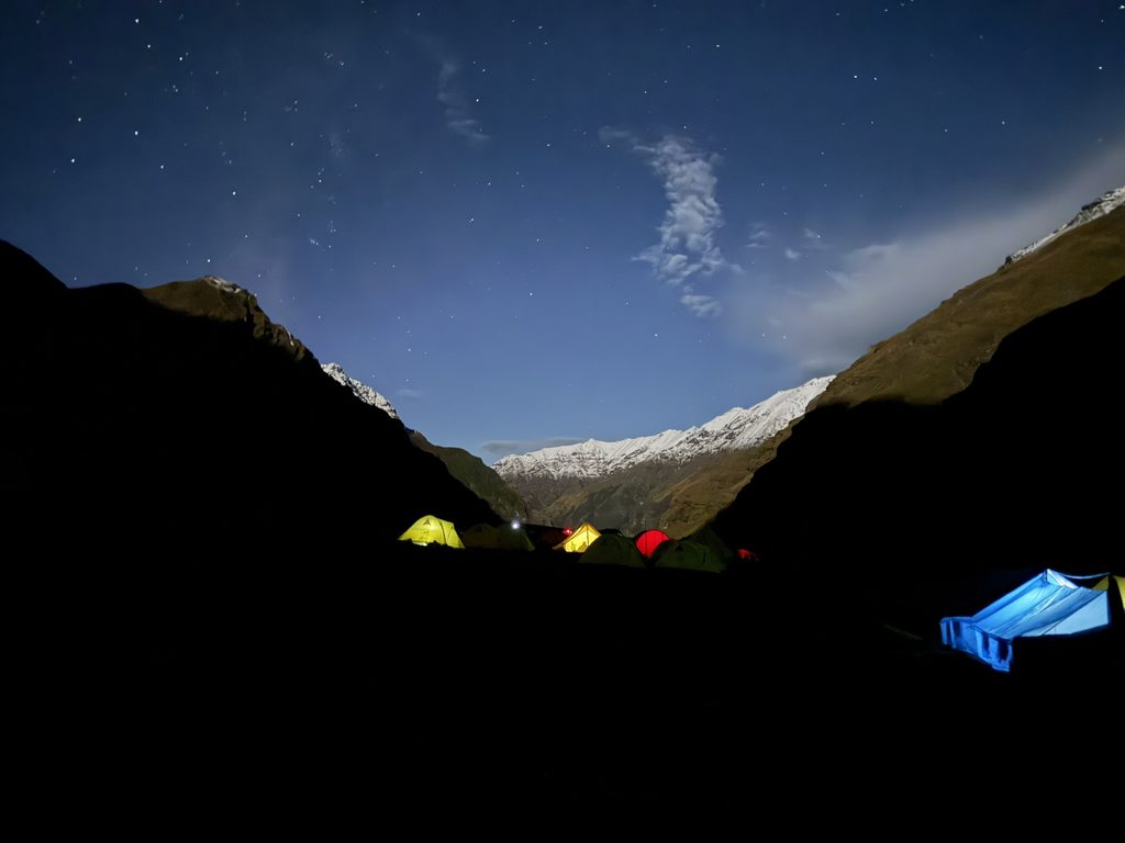 Illuminated trekking tents beneath a star-filled Himalayan sky