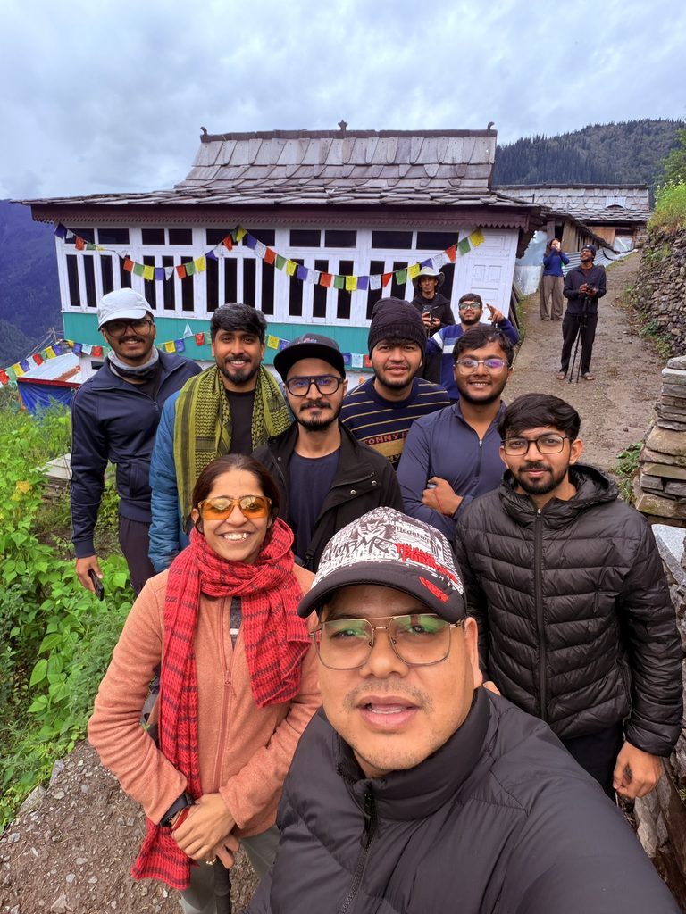 Trekking group posing outside a traditional wooden temple in Dhara village near Jakha.