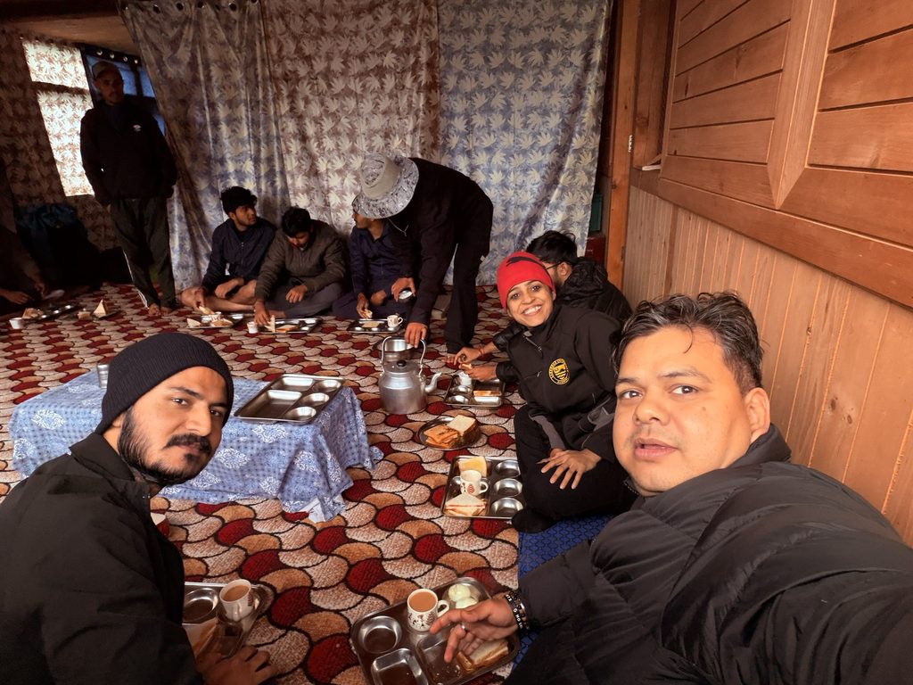 Trekkers sharing a simple meal inside a traditional mountain homestay in Jiskun village during the Rupin Pass trek.